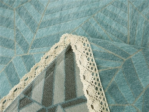 Detail of teal chenille sofa cover with golden geometric lines and white lace edges
