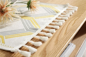Detail of chenille table runner with yellow geometric lines and white cotton tassels