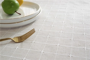 Close-up of beige plaid tablecloth with refined cross-stitch texture and fringe detail