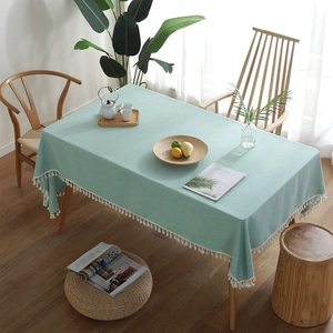 Minimalist mint green rectangular tablecloth with white fringe on a wooden table