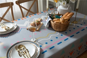 Close-up of modern gray tablecloth with colorful geometric patterns in a cozy dining setting