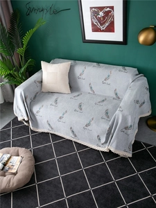 Detail of gray chenille sofa cover featuring feather patterns and elegant lace edges
