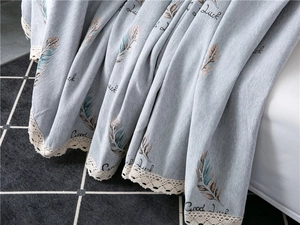 Detail of blue chenille sofa cover with feather pattern and white crochet lace trim