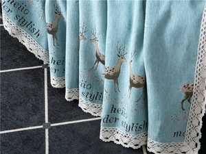 Close-up of blue chenille sofa cover with deer pattern and delicate lace edges