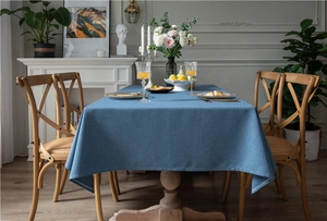 Close-up of dark blue linen-textured tablecloth on wooden table with elegant home decor