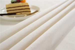 Close-up of thick beige tablecloth showing coarse linen texture with elegant table setting