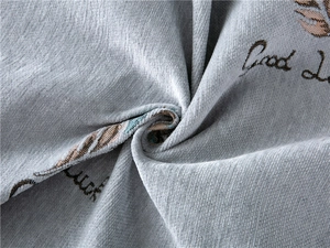 Close-up of thick chenille sofa cover with brown leaf patterns and Good Luck embroidery