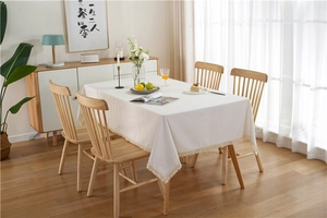 Close-up of white minimalist tablecloth featuring beige fringe tassels and cotton linen texture