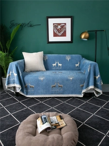 Detail of blue chenille sofa cover with deer pattern and white lace edge in a cozy room