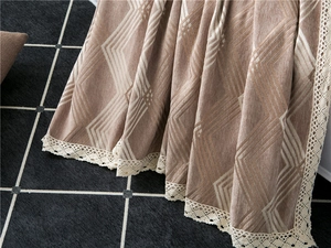 Detail of chenille sofa cover showing geometric patterns and white lace trim edge