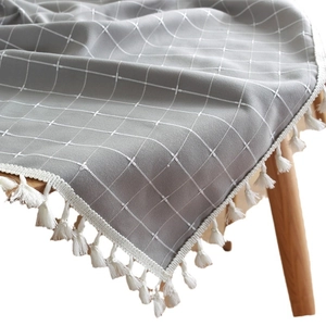 Gray rectangle tablecloth with white grid pattern and tassel edges on wood table