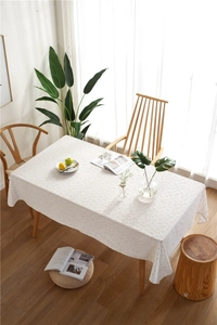 Detail of off-white cotton tablecloth with yellow polka dots on a wooden dining table