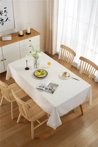 Close-up of thick off-white tablecloth with elegant tassel fringe and textured cotton linen