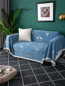 Close-up of thick blue chenille sofa cover featuring white deer patterns and lace edges