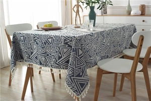 Vista detallada de un mantel jacquard con patrón de triángulos y elegantes flecos de borlas