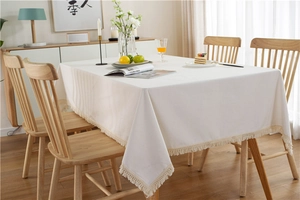Detailed close-up of cream rectangular tablecloth with fine fringe and boho texture