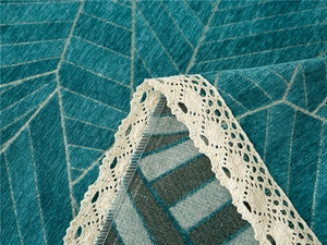 Detail of chenille sofa cover with teal geometric jacquard and cream lace edging