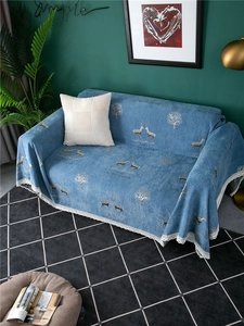 Detail of blue chenille sofa cover with golden deer pattern and white lace edge