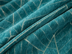Close-up of thick chenille sofa cover fabric with teal geometric patterns and texture