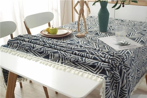 Detalle de patrones jacquard geométricos y flecos con borlas en un mantel azul marino