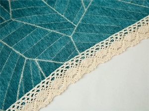Macro detail of teal chenille sofa cover with golden geometric lines and ivory lace trim