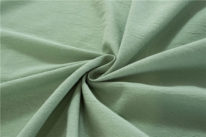 Makroaufnahme von salbeigrüner Baumwolle mit natürlicher Knitteroptik und weichem Fall