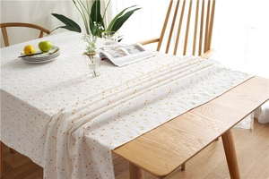 Detail of white cotton tablecloth with orange polka dots on a natural wooden table