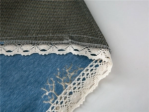 Macro detail of blue chenille fabric with deer embroidery and white lace edging
