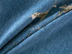 Close-up of thick blue chenille fabric featuring elk motifs and woven lucky text detail