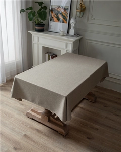 Detailed texture of beige linen-style tablecloth draped over a wooden dining table
