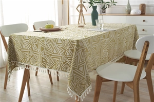 Detalle de mantel geométrico amarillo mostaza con flecos de borlas de algodón blanco suave