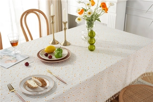 Detail of yellow polka dot cotton tablecloth with decorative fringe in a cozy dining setting