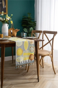 Detail of grey polyester table runner featuring colorful citrus embroidery and bead tassels