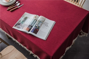 Close-up of deep red tablecloth with elegant white tassel fringe and woven texture detail