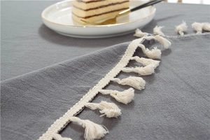 Detailaufnahme der grauen Tischdecke aus Baumwolle mit cremefarbenen Quasten am Rand