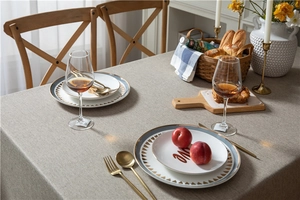 Detail of grey faux linen tablecloth with gold-rimmed ceramic plates and cutlery