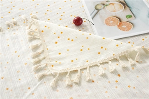 Detail of cotton tablecloth with orange polka dots and elegant white fringe borders