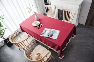 Close-up of wine red rectangular tablecloth with elegant cream fringe in Nordic interior