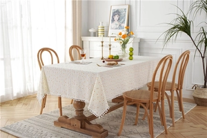 Detailed view of cream-colored cotton tablecloth with orange polka dots and white pom-pom trim