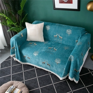 Detail of chenille sofa cover with golden reindeer pattern and white lace edge