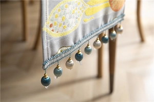Detail of light gray table runner with colorful tassels and gold metal buckle accents