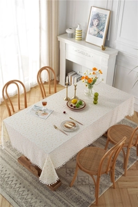 Detail of cotton tablecloth with orange polka dots and white pom-pom tassel fringe