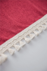 Detail of red woven fabric with white tassel fringe in a bohemian minimalist style