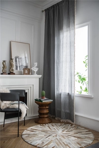 Detail of grey herringbone curtain with cream tassel edge in a modern interior setting
