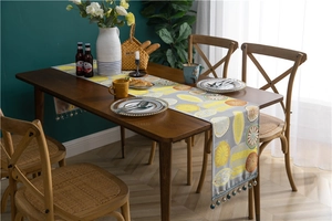 Macro view of modern polyester table runner featuring lemon patterns and beaded tassels