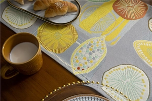 Detailed view of grey jacquard table runner with citrus pattern and woven texture