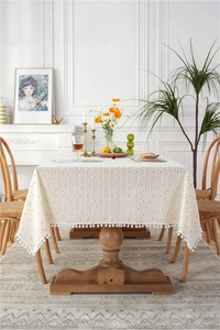 Close-up of beige tablecloth with orange polka dots and white pom-pom trim details