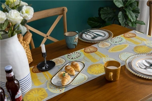 Detailed close-up of a grey table runner with vibrant lemon patterns on dark wood
