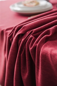 Macro shot of dark red textured tablecloth with thick fabric folds and elegant drape details