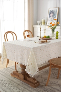 Detailed texture of cotton jacquard tablecloth with orange polka dots and white pompom trim